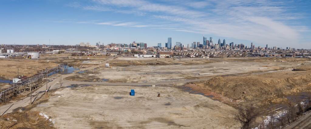 refinery_demo_NorthYard_CourtesyHilco The former refinery is visible in the distance, with a bare, dirt field in the foreground.