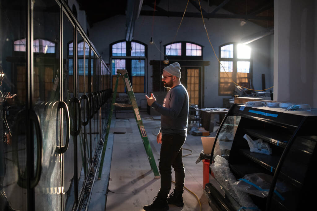 Vincent Finazzo gestures while standing inside a warehouse under construction