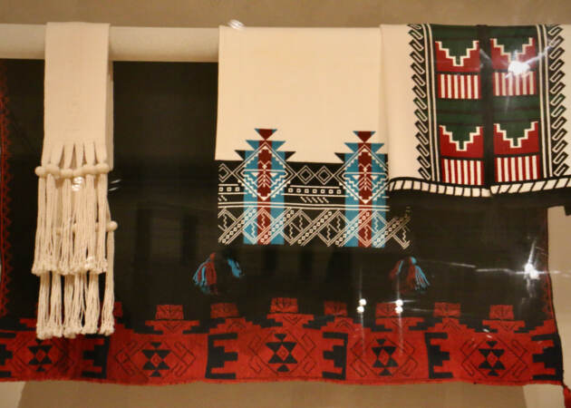 Traditional Pueblo dance garments hand above pottery at The Barnes' exibit ''Water, Wind, Breath.'' (Emma Lee/WHYY)