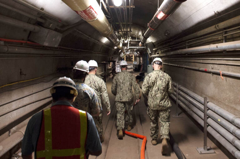 In this Dec. 23, 2021, photo provided by the U.S. Navy, Rear Adm. John Korka, Commander, Naval Facilities Engineering Systems Command (NAVFAC), and Chief of Civil Engineers, leads Navy and civilian water quality recovery experts through the tunnels of the Red Hill Bulk Fuel Storage Facility, near Pearl Harbor, Hawaii. The Navy is scrambling to contain what one lawmaker has called a “crisis of astronomical proportions” after jet fuel leaked from an 80-year-old Hawaii tank farm, seeped into a drinking water well and polluted the water streaming out of faucets in Pearl Harbor military housing