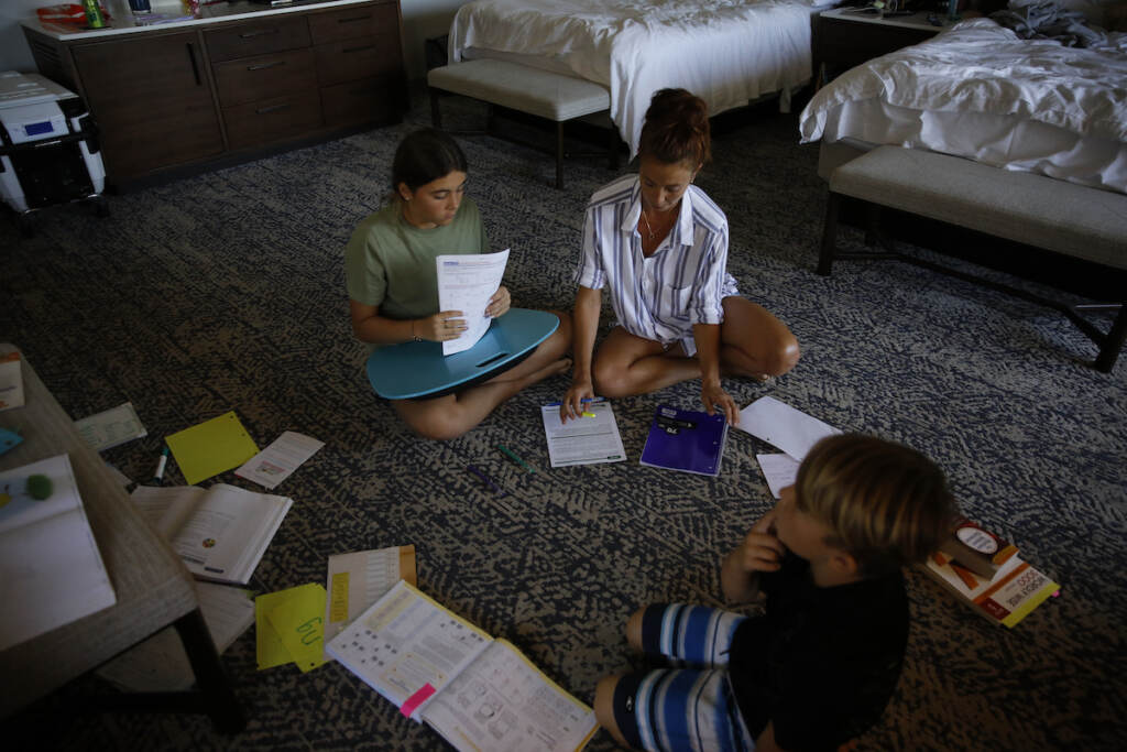 Lauren Wright, center, teaches her son, Jaxson Wright, 7, right, and her daughter, Gianna Wright, 13, left, in a Waikiki hotel room on Friday, Jan. 28, 2022 in Honolulu. The family is among thousands forced to leave their military housing because of jet fuel contamination in their water supply. Her Navy husband and three children ranging in age from 7 to 17 have spent two months living in hotels after water smelling like fuel started pouring out of faucets at their home near Pearl Harbor