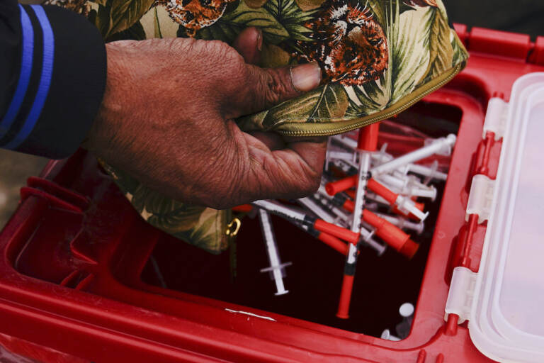 Keith Lewis disposes of used syringes at a needle exchange run by Camden Area Health Education Center in Camden, N.J., Thursday, Feb. 24, 2022. (AP Photo/Matt Rourke)