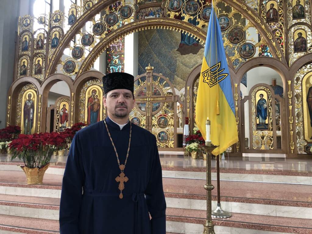 Father Roman Pitula of the Philadelphia Ukrainian Catholic Church, standing near a candle the church lit to pray for Ukraine. (Emily Rizzo _ WHYY News) Father Roman Pitula of the Philadelphia Ukrainian Catholic Church, standing near a candle the church lit to pray for Ukraine