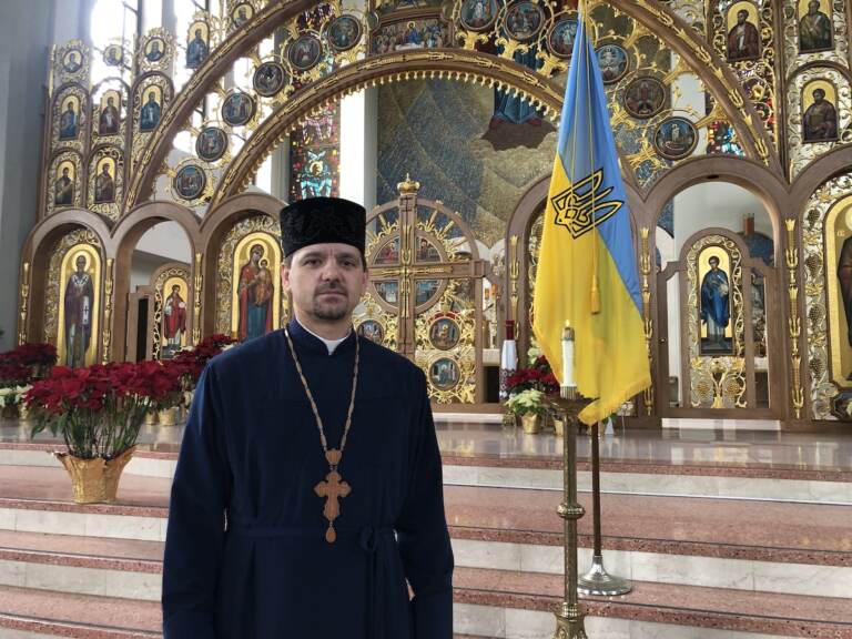 Father Roman Pitula of the Philadelphia Ukrainian Catholic Church, standing near a candle the church lit to pray for Ukraine