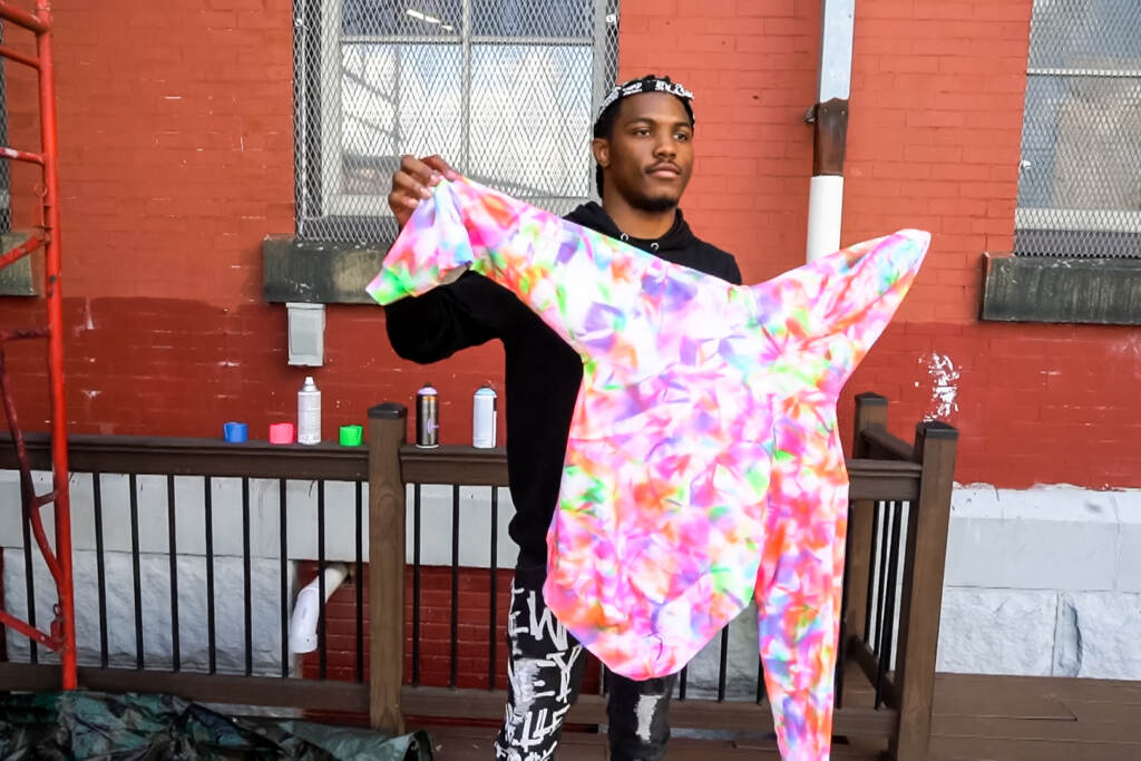 M&M-kreate-hub A clothing designer and artist from Kreate Hub holding up a tie dye sweatshirt he made
