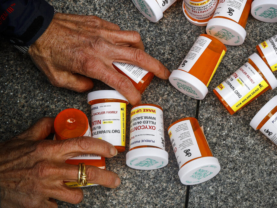 A protester gathers containers that look like OxyContin bottles at an anti-opioid demonstration in front of the U.S. Department of Health and Human Services headquarters in Washington in 2019. A protester gathers containers that look like OxyContin bottles at an anti-opioid demonstration in front of the U.S. Department of Health and Human Services headquarters in Washington in 2019.
(Patrick Semansky/AP)