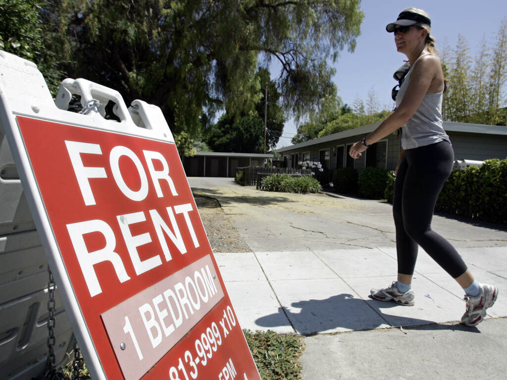 A for rent sign in Palo Alto, California. Across the country rents are on the rise, in part due to a historic shortage of homes either to rent or buy. A woman walks next to a