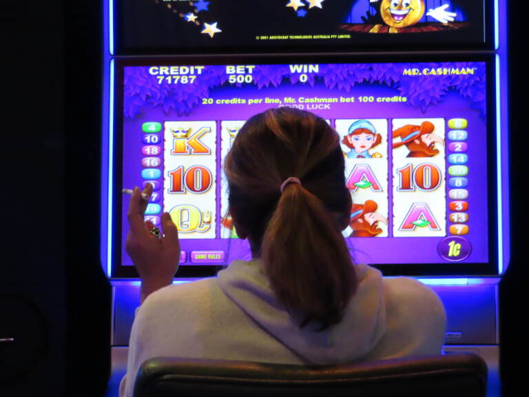 A gambler smokes while playing a slot machine