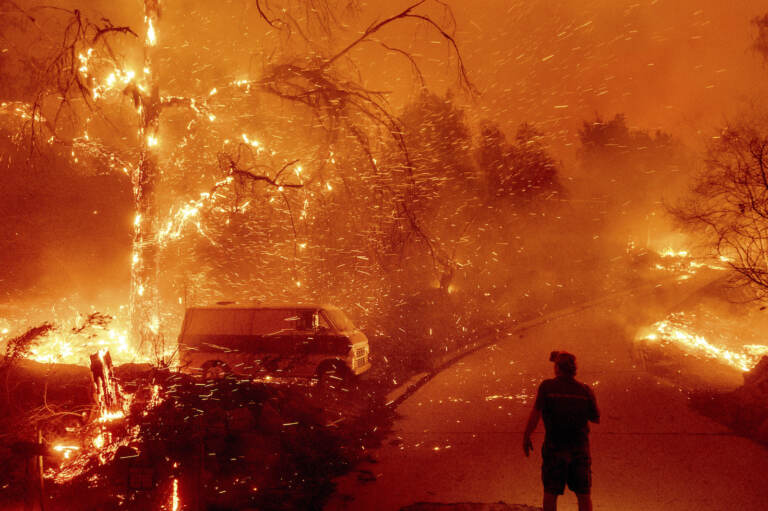 Bruce McDougal watches embers fly over his property as the Bond Fire burns through the Silverado communit
