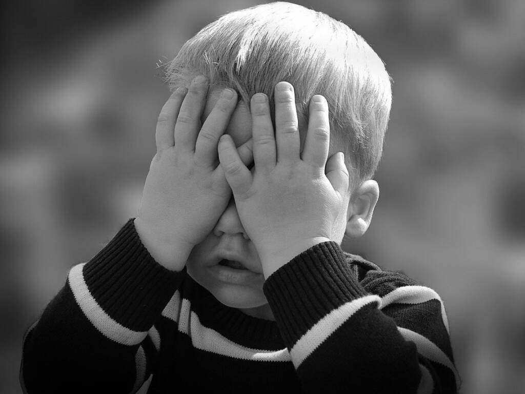 Sad child A child covers his face with his hands.