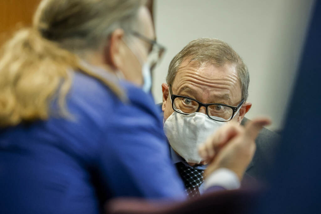 Greg McMichael, center, listens to his attorney during his 2021 state murder trial. McMichael, his son Travis McMichael, and neighbor William “Roddie” Bryan are now on trial for committing federal hate crimes against Ahmaud Arbery. Greg McMichael, center, listens to his attorney Franklin Hogue during the sentencing of he and his son Travis McMichael, and a neighbor, William