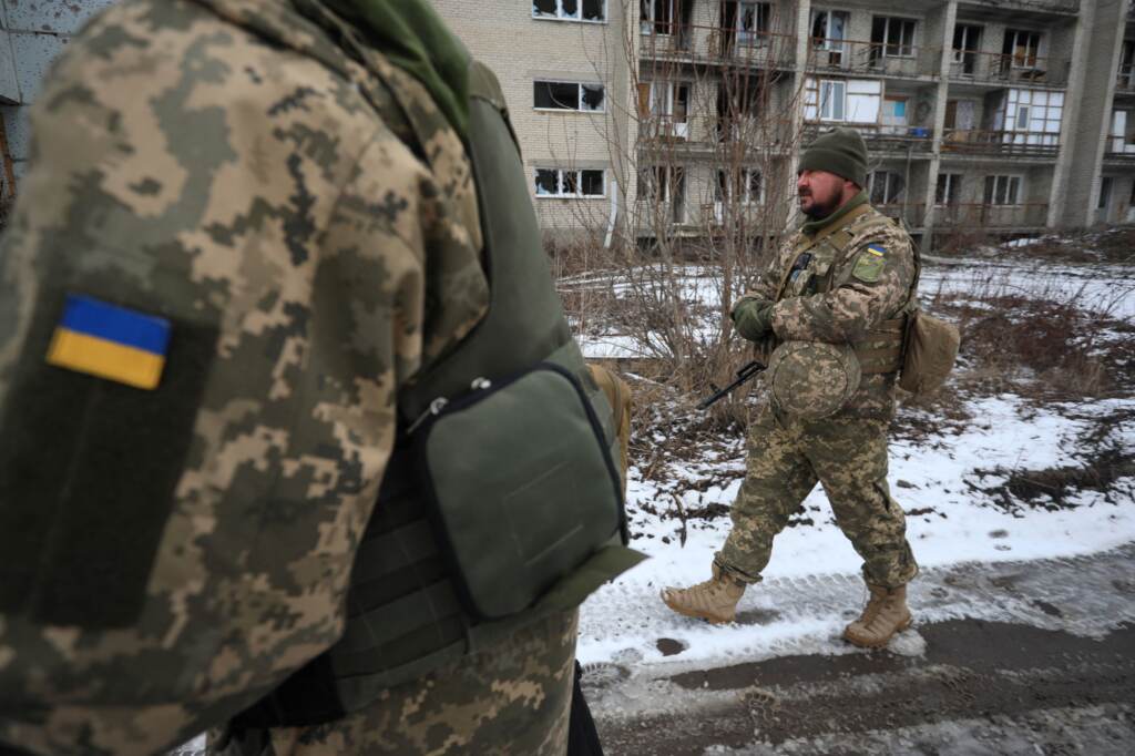 Ukrainian military forces walk in front of damaged buildings on the front line with Russia-backed separatists in Mariinka in the Donetsk region on Feb. 7.