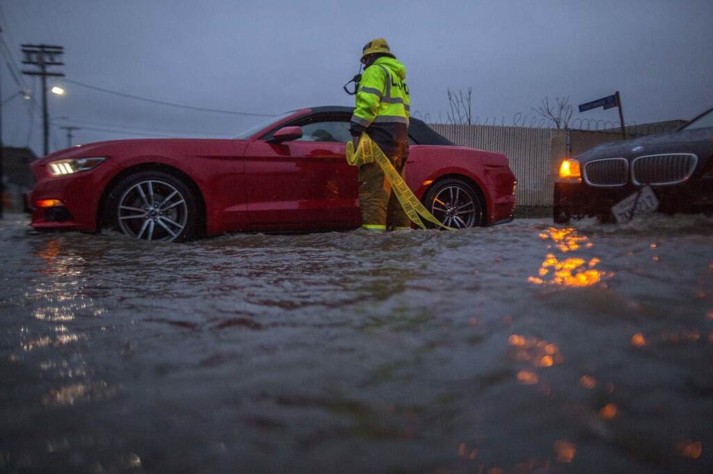 A firefighter checks on stalled cars on a flooded street