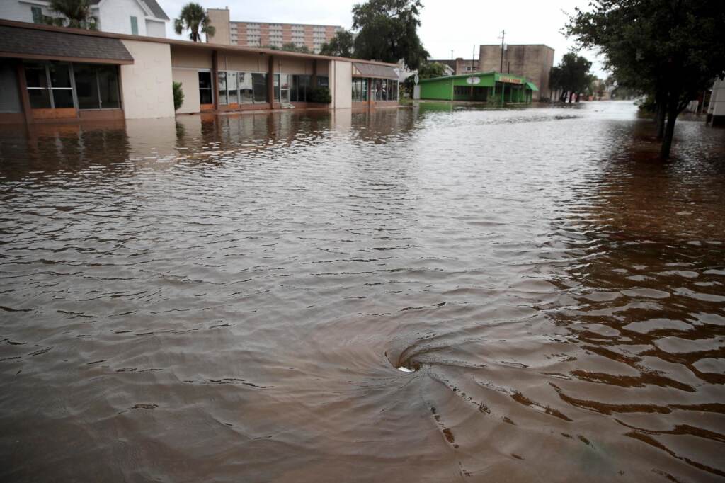 Water drains from a street flooded by rain from Hurricane Harvey
