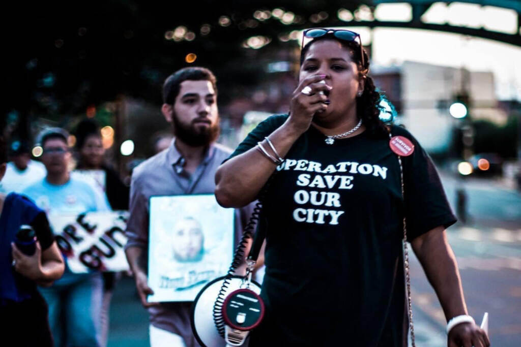 good-souls-RozPic Rosalind Pichardo leading a crowd of people with a megaphone, wearing an