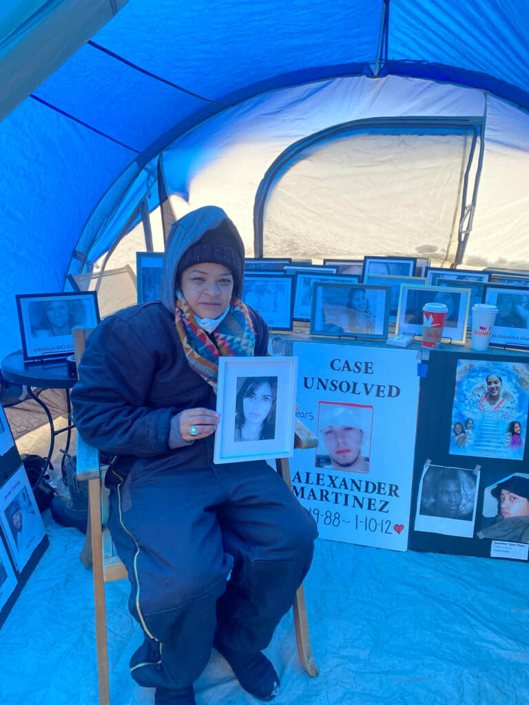 Rosalind Pichardo camping outside surrounded by photos of victims of homicide