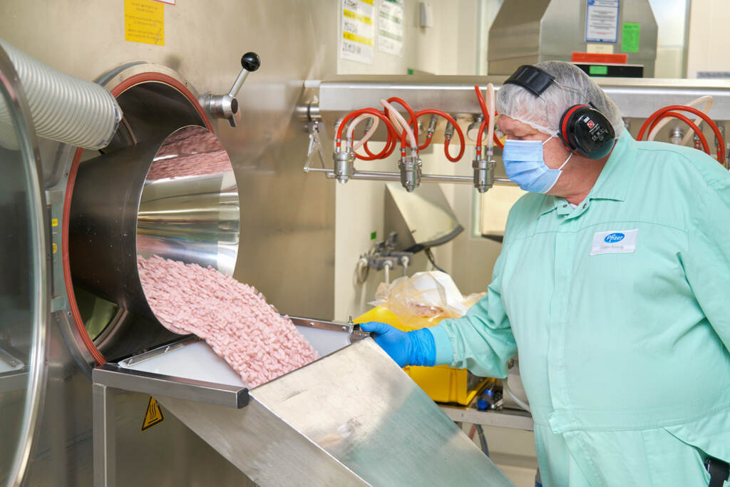 A lab technician at a Pfizer factory inspects Paxlovid tablets