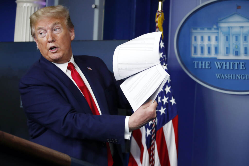 Donald Trump President Donald Trump holds up papers while he speaks from a podium
