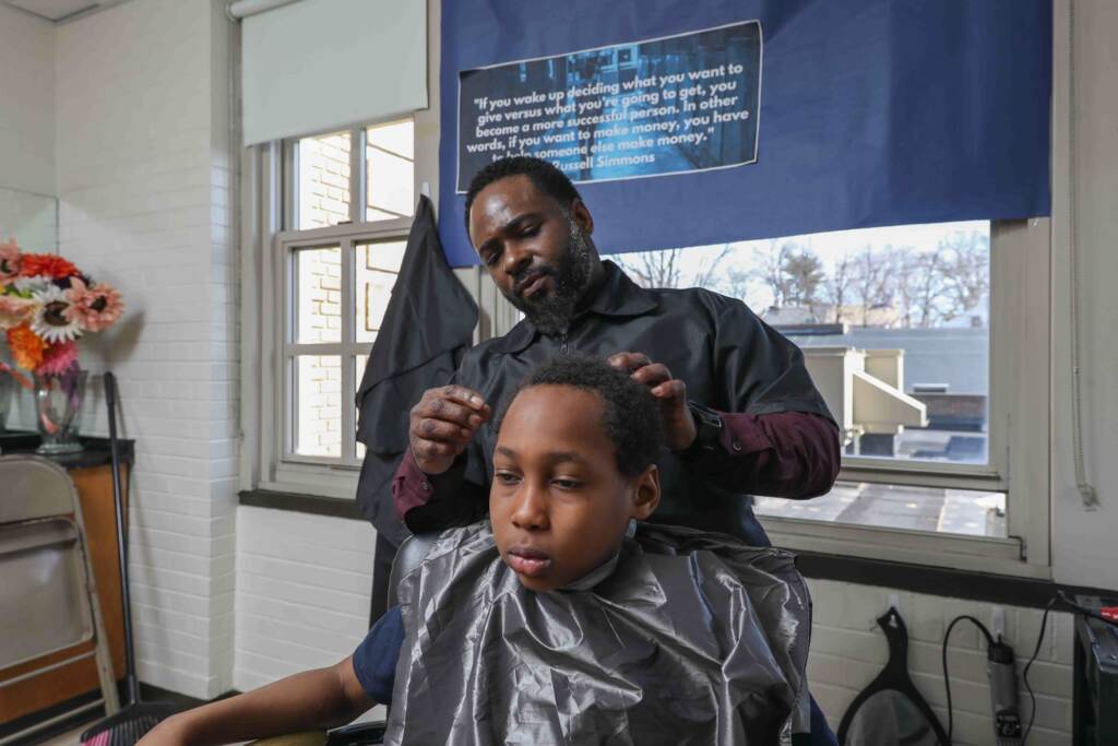 2020 03 05-s stimpson-terrance newton elijah jackson-wilmington warner elementary-principal gives haircuts Terrance Newton cuts the hair of Warner student Elijah Jackson in March 2020, days before the pandemic shut down schools and his school barbershop. (Saquan Stimpson for WHYY)