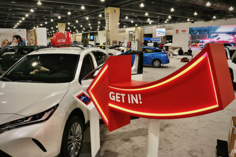 A sign invites visitors to sit in the cars at the Philadelphia Auto Show. (Emma Lee/WHYY)
