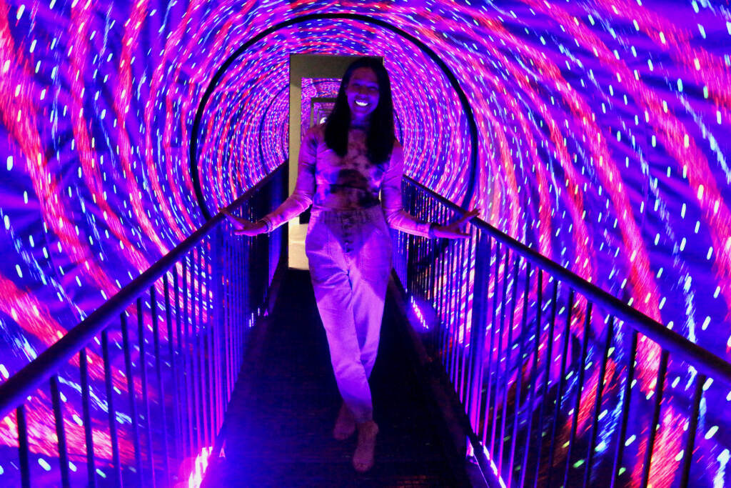 2022 03 09-e lee-stacy rangel stec-philadelphia museum of illusions-opening tunnel Stacy Rangel Stec walks through a tunnel whose swirling lights create an illusion of motion at the Museum of Illusions in Philadelphia. (Emma Lee/WHYY)