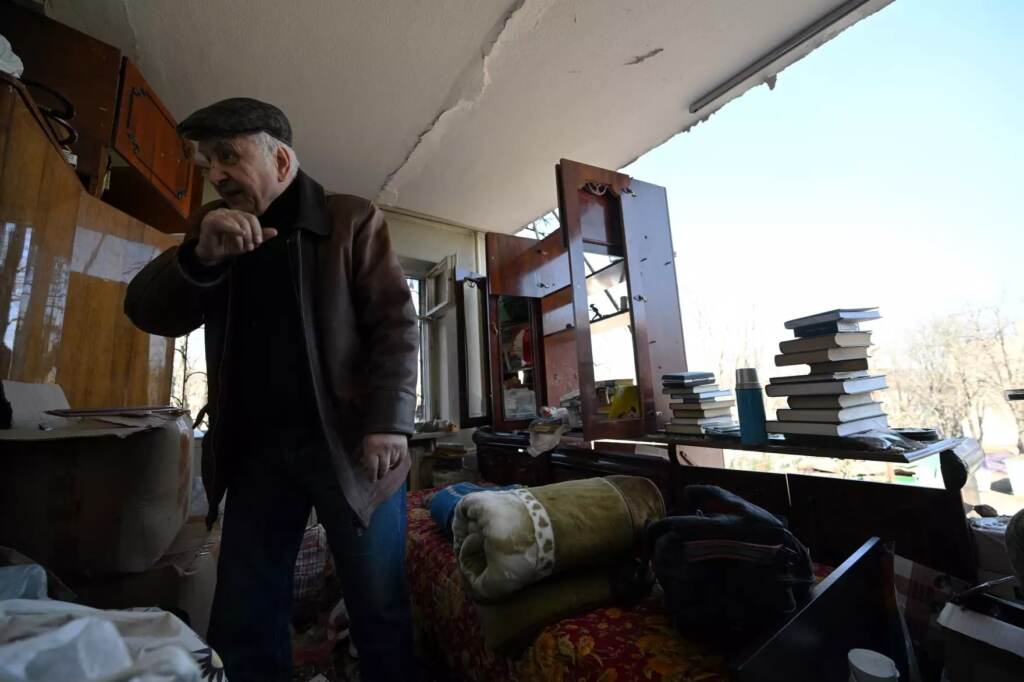 A local resident collects the belongings out of his apartment in Kyiv on Sunday in a five-story residential building that partially collapsed after a shelling by Russian troops. (Sergei Supinsky/AFP via Getty Images)