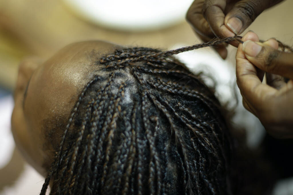 Congress Hair Discrimination Shelly Smith braids hair for Bridget Dunmore at her salon, Braid Heaven Tuesday, Jan. 28, 2020 in Kansas City, Kan. (AP Photo/Charlie Riedel)