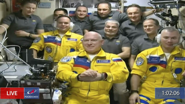 In this frame grab from video provided by Roscosmos, Russian cosmonauts Sergey Korsakov, Oleg Artemyev and Denis Matveyev are seen during a welcome ceremony after arriving at the International Space Station, Friday, March 18, 2022, the first new faces in space since the start of Russia’s war in Ukraine. The crew emerged from the Soyuz capsule wearing yellow flight suits with blue stripes, the colors of the Ukrainian flag
