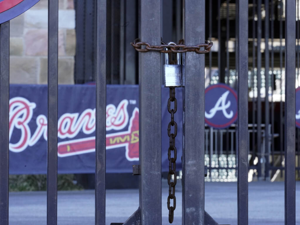 Locked gates are shown at Truist Park home of the Atlanta Braves baseball team Wednesday, March 2, 2022, in Atlanta. MLB commissioner Rob Manfred has canceled the first two series for each of the 30 teams, cutting each club's schedule from 162 games to likely 156 at most