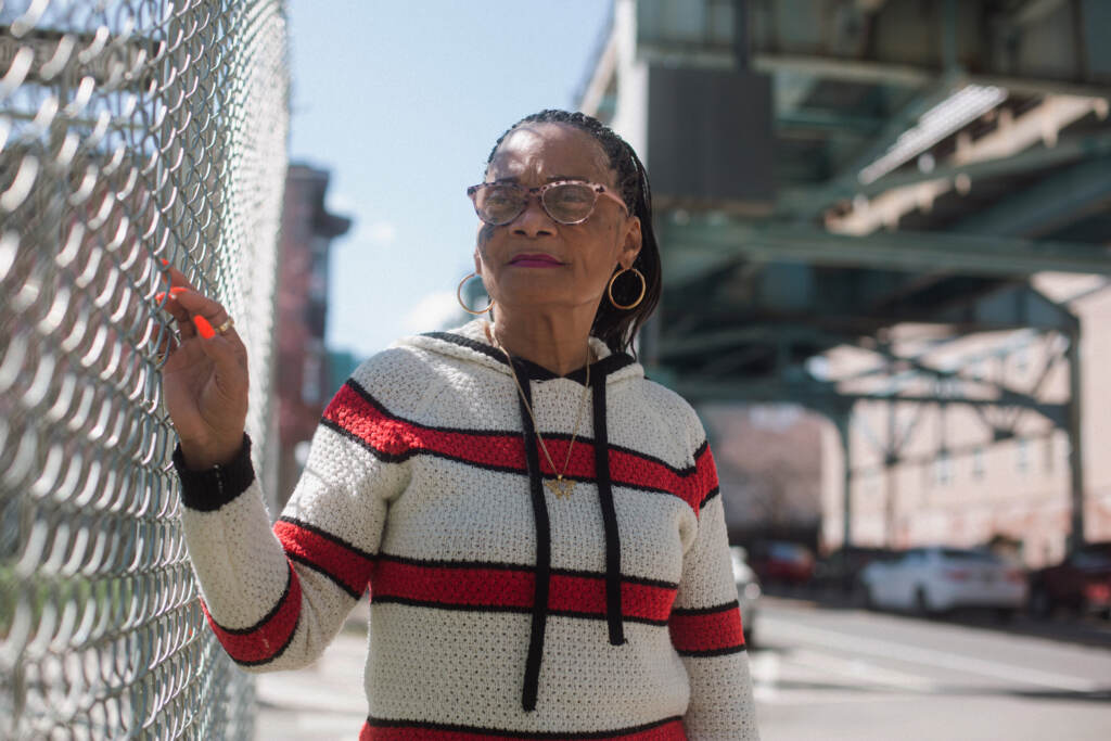 Brenda Mosley stands next to a fence under the El