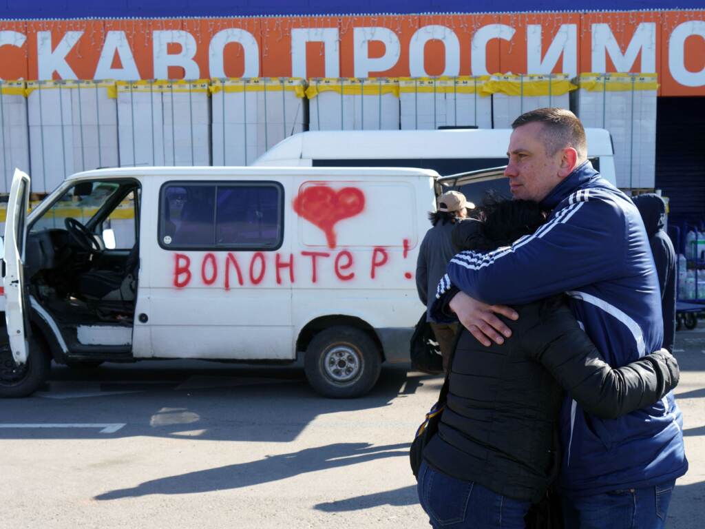 Olga and Oleksandr hug as they wait beside a vehicle painted with the word “volunteers” at an evacuation center in Zaporizhzhya, Ukraine, on Tuesday. Olga’s father is stuck in Mariupol, and Oleksandr is hoping to get in a volunteer convoy to the city, now under Russian siege. Olga and Oleksandr hug as they wait beside a vehicle painted with the word