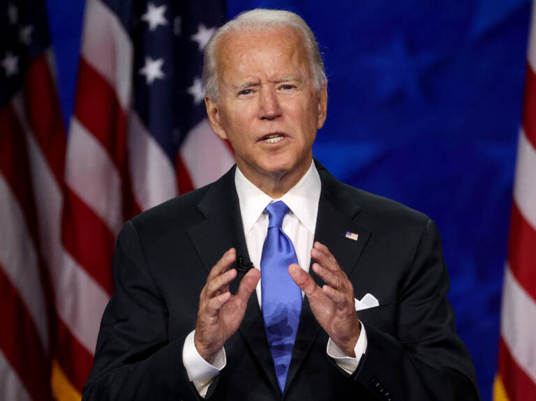 President Biden is speaking in front of an American flag.