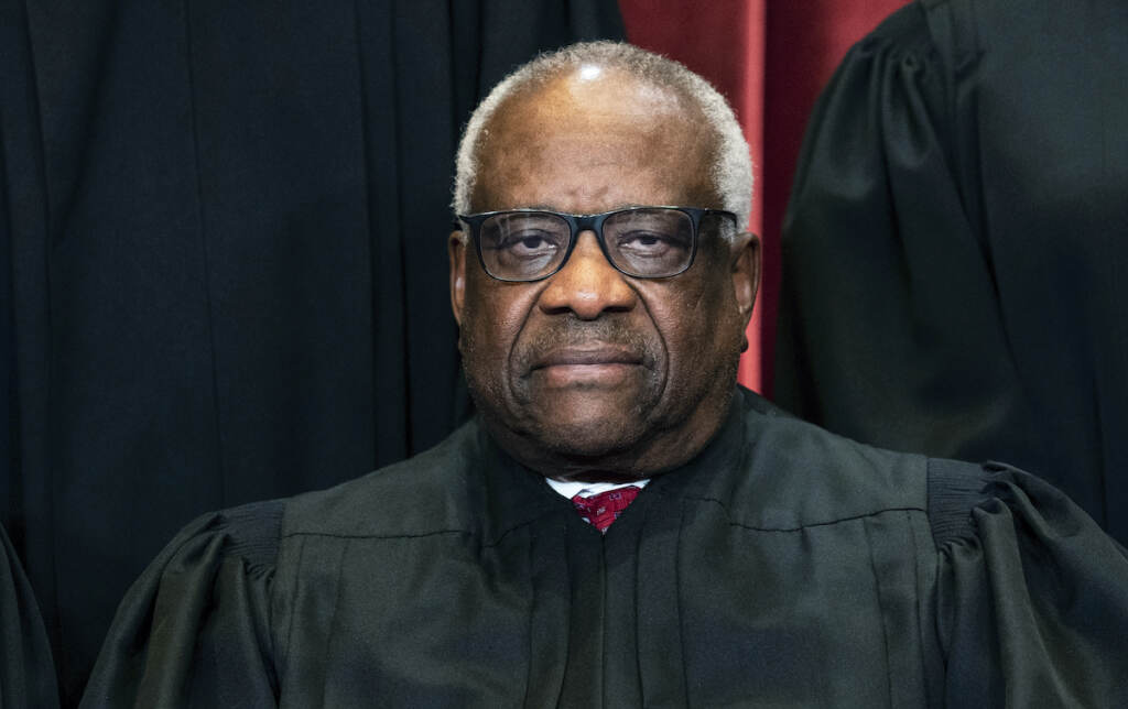 Associate Justice Clarence Thomas sits during a group photo