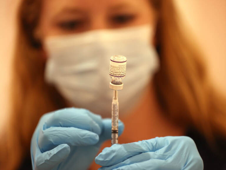 Ashley McGee fills a syringe with the Pfizer COVID-19 booster vaccination