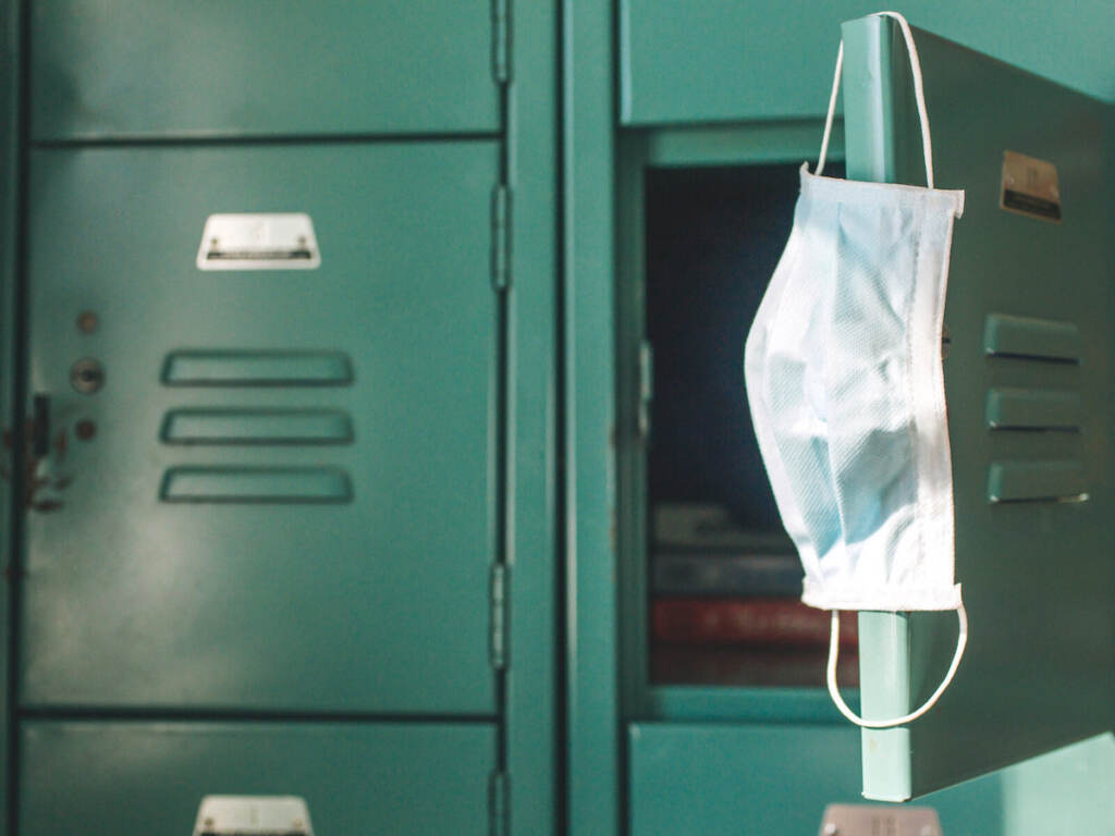 COVID-19 School, Face Mask School A surgical mask hangs from the open door of a green locker.