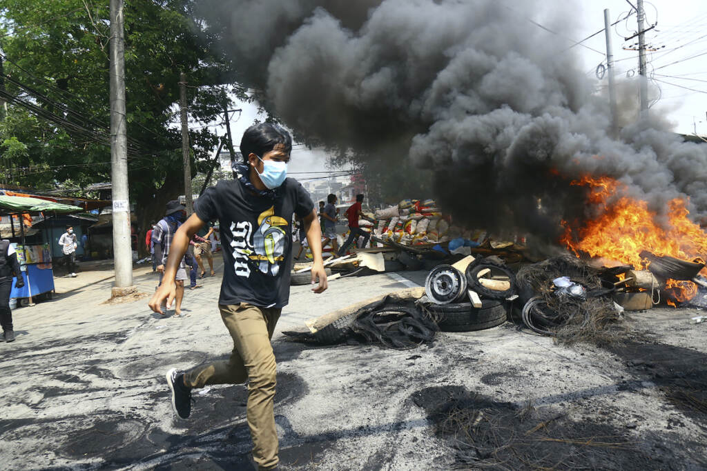YE Reporter’s Notebook Myanmar Anti-coup protesters run around a burning, makeshift barricade
