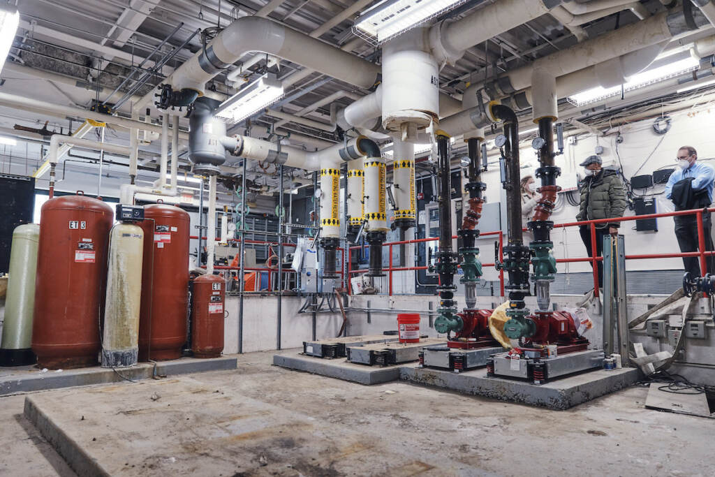 A group of people stands in a boiler room.