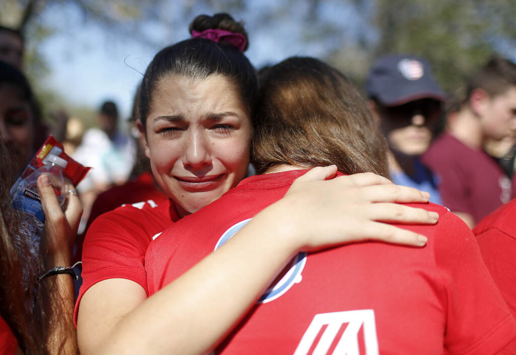 File photo: A student mourns the loss of her friend during a community vigil at Pine Trails Park, Thursday, Feb. 15, 2018, in Parkland, Fla., for the victims of the shooting at Marjory Stoneman Douglas High School. She is crying as she embraces someone.