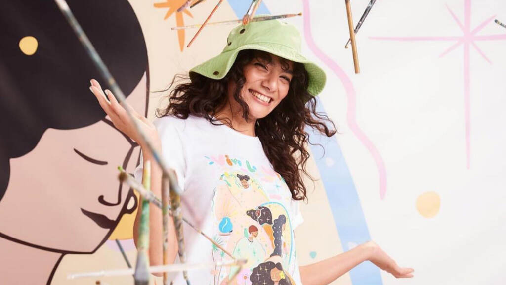 Manuela Gillén gestures while smiling in front of a mural