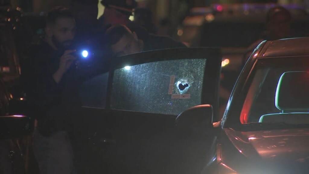 ppd-south-philly-police-shooting-wpvi-030222 A police officer shines a flashlight onto a car window with a bullet hole in it