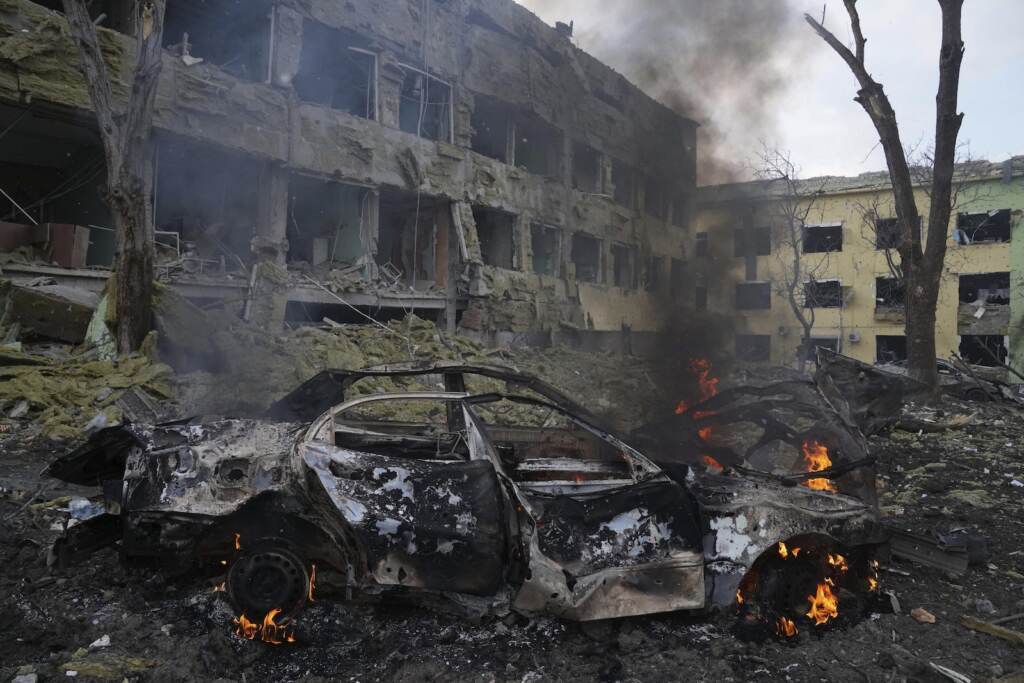 Russia Ukraine War A car burns at the side of the damaged by shelling maternity hospital
