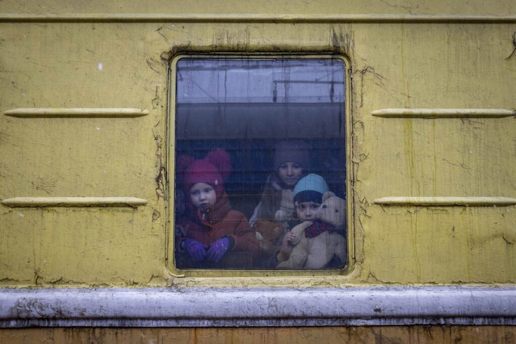Children Vlada, left, Katrin and Danilo look out from a window of an unheated train carriage