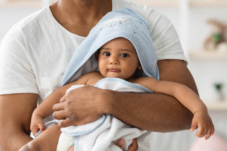 A baby wrapped in a towel and held by a man
