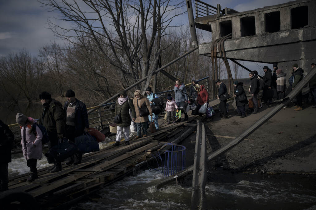 Russia Ukraine War Ukrainians cross an improvised path under a destroyed bridge while fleeing Irpin