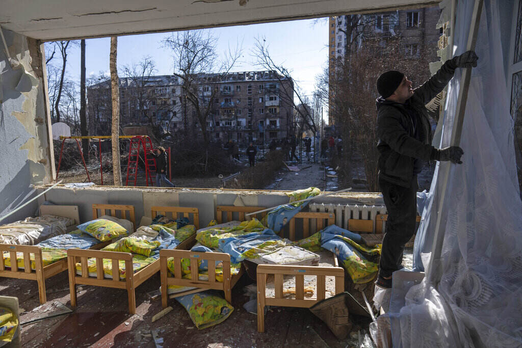 APTOPIX Russia Ukraine War A man removes a destroyed curtain inside a school damaged among other residential buildings in Kyiv, Ukraine, Friday, March 18, 2022.