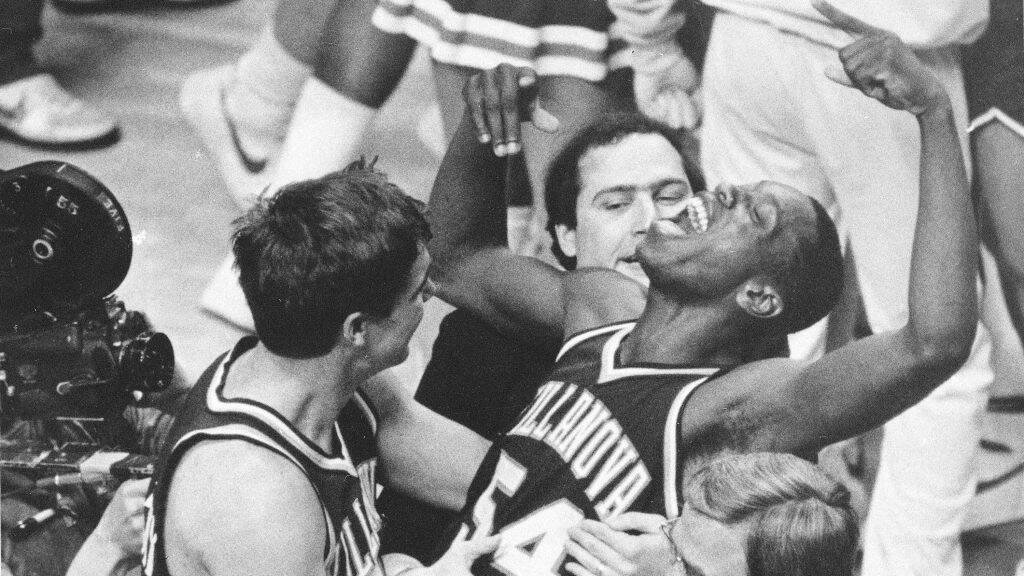 In a black-and-white photo, a group of Villanova basketball players celebrate.