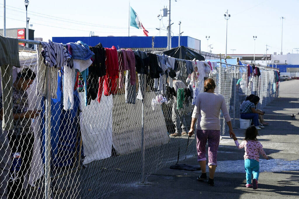 Border Asylum Limits Politics Migrants walk along a fence at a makeshift camp that is a temporary home for hundreds of migrants hoping to seek asylum in the United States at a pedestrian crossing on Nov. 8, 2021, in Tijuana, Mexico.