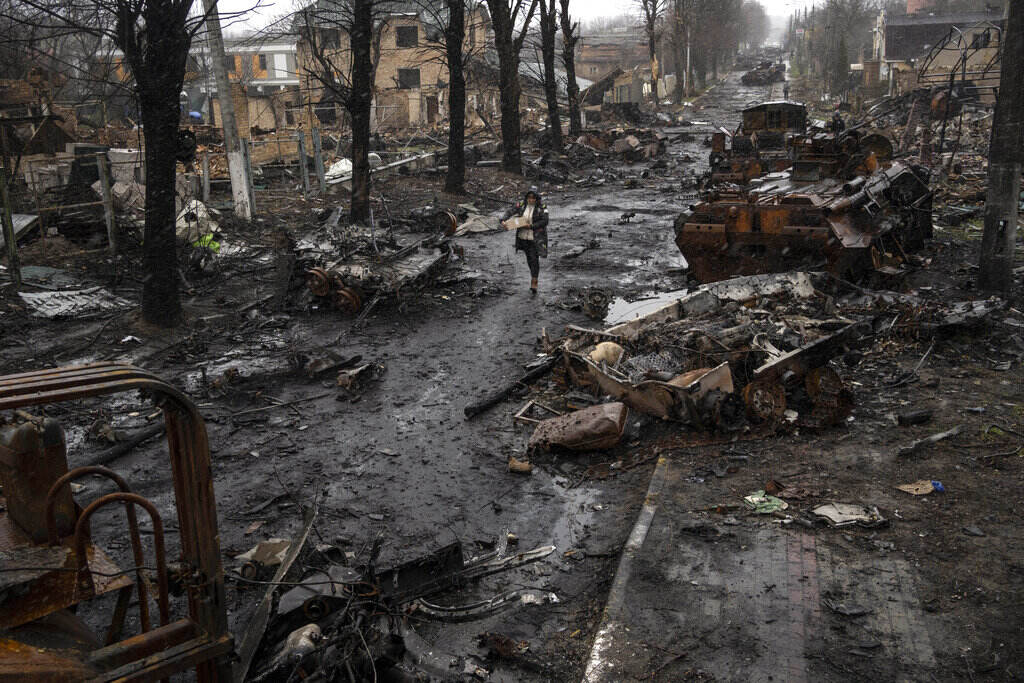 APTOPIX Russia Ukraine War A woman walks amid destroyed Russian tanks in Bucha, in the outskirts of Kyiv, Ukraine, Sunday, April 3, 2022.