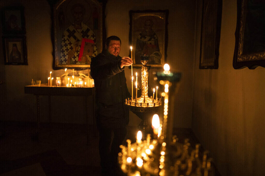 Russia Ukraine War A man lights a candle during a Sunday service in an Orthodox church in Bucha, in the outskirts of Kyiv, Ukraine, Sunday, April 10, 2022.