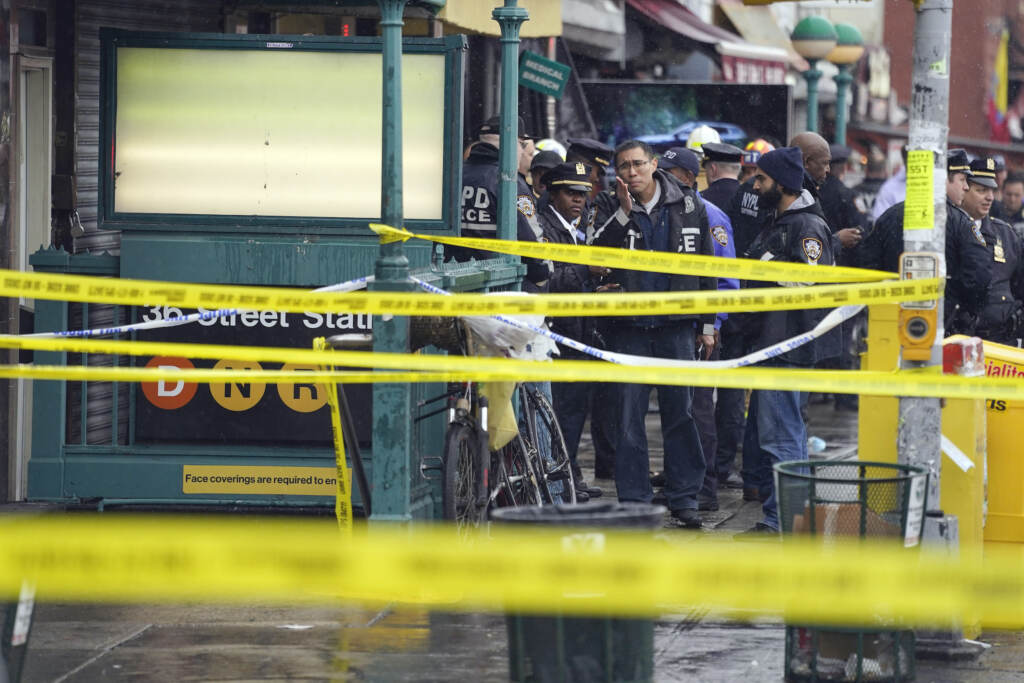 APTOPIX Subway-Shooting New York City Police Department personnel gather at the entrance to a subway stop in the Brooklyn borough of New York, Tuesday, April 12, 2022. Multiple people were shot and injured Tuesday at a subway station in New York City during a morning rush hour attack that left wounded commuters bleeding on a train platform. (AP Photo/John Minchillo)